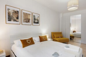 Quarto de hotel com cama, cadeira, espelho e quadros na parede.