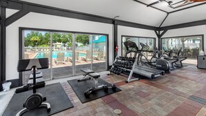 Un gimnasio con equipo de ejercicio, una banca y un estante con mancuernas.