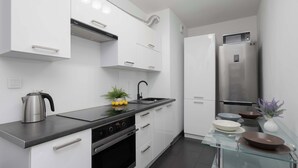 Una cocina moderna con armarios blancos, electrodomésticos de acero inoxidable y una mesa de comedor de vidrio.