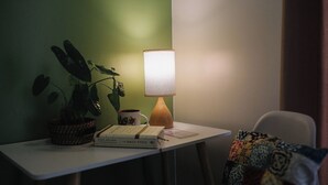 A small table with a lamp, a plant, a mug, and books.
