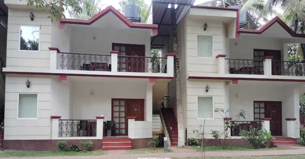 Un edificio residencial de dos pisos con balcones, una escalera y una entrada principal.