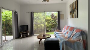 Ein geräumiges Wohnzimmer mit einer schwarzen Couch, einem Couchtisch und einem Fernseher.