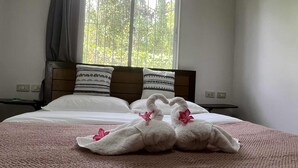 Ein Bett mit weißer Bettwäsche, zwei Kissen mit schwarzen Mustern und zwei Handtücher in Schwanenform mit rosa Blumen.