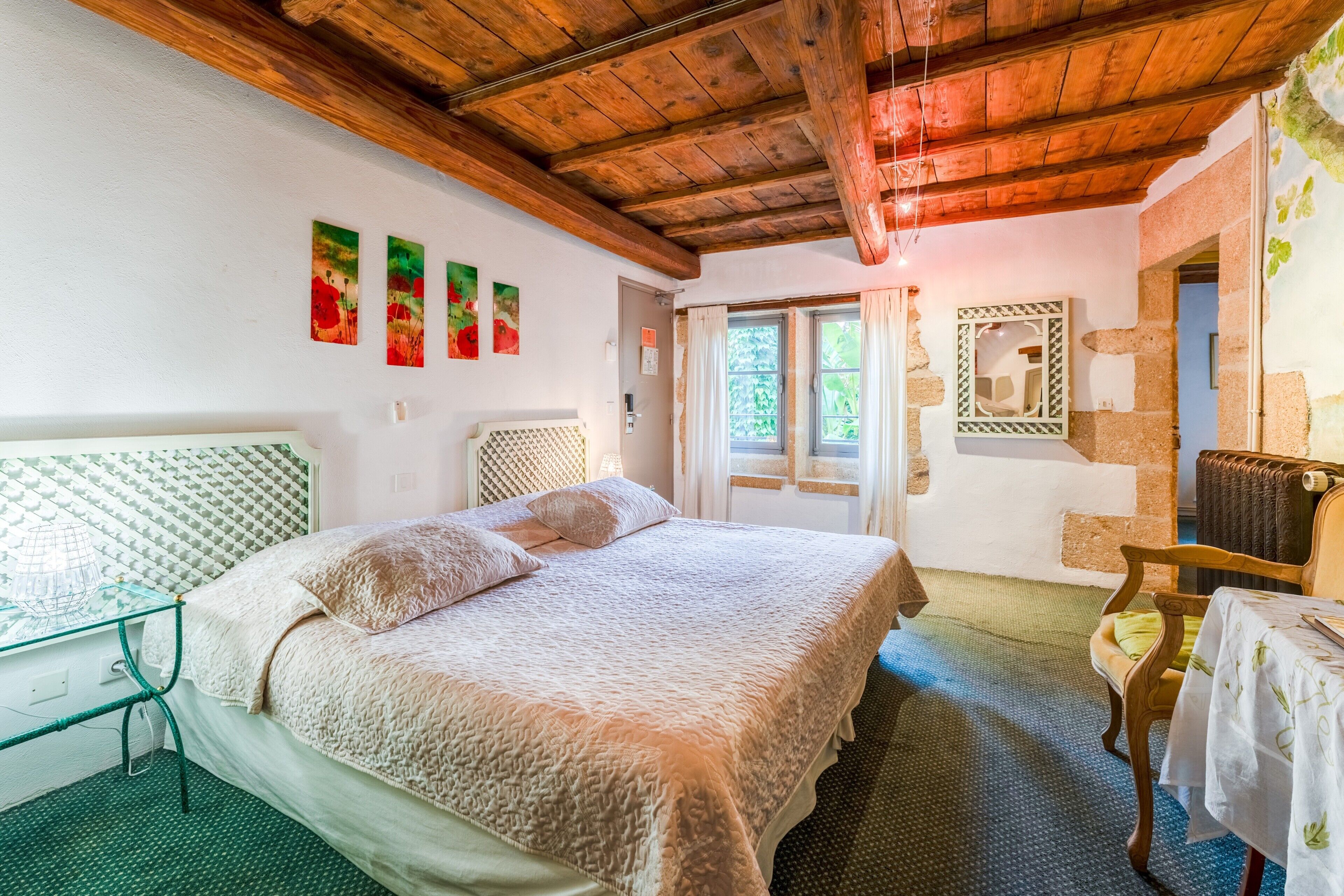 Een slaapkamer met een bed, een glazen tafel, een spiegel en een deur naar een andere kamer.