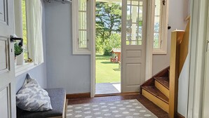 A room with a wooden staircase, a bench, a patterned rug, and a door leading to a garden. - Charming house with kayaks, 300m from the sea on Orust | SE09139 (Henån)