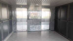 Una habitación amplia con suelo de baldosas, grandes puertas correderas de vidrio y un diseño moderno de techo.