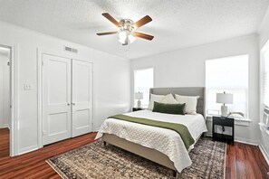 Ein Schlafzimmer mit Bett, Deckenventilator, Fenster und Nachttisch.