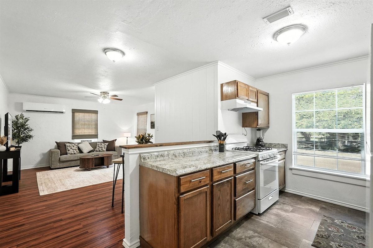 A modern kitchen with wooden cabinets, a granite countertop, and a built-in oven.