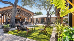 An outdoor seating area with tables and chairs, surrounded by potted plants and a pergola structure. - Relax at Coral Cove – Poolside Paradise in Bonita Springs (Bonita Springs)