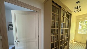 A hallway with a white door, a glass-fronted cabinet, and a patterned floor.