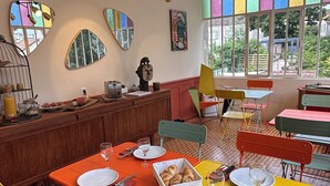 A dining area with a checkered floor, yellow and orange tables, and a variety of chairs.
