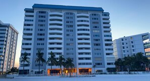 A multi-story hotel with balconies, palm trees, and a beach view. - The Beach House 2 Bedroom Condo (Sarasota)