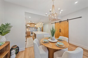A modern kitchen with a central island, white cabinetry, and a hanging light fixture.