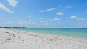 Una playa con agua turquesa cristalina, una orilla de arena y un horizonte con edificios de la ciudad.