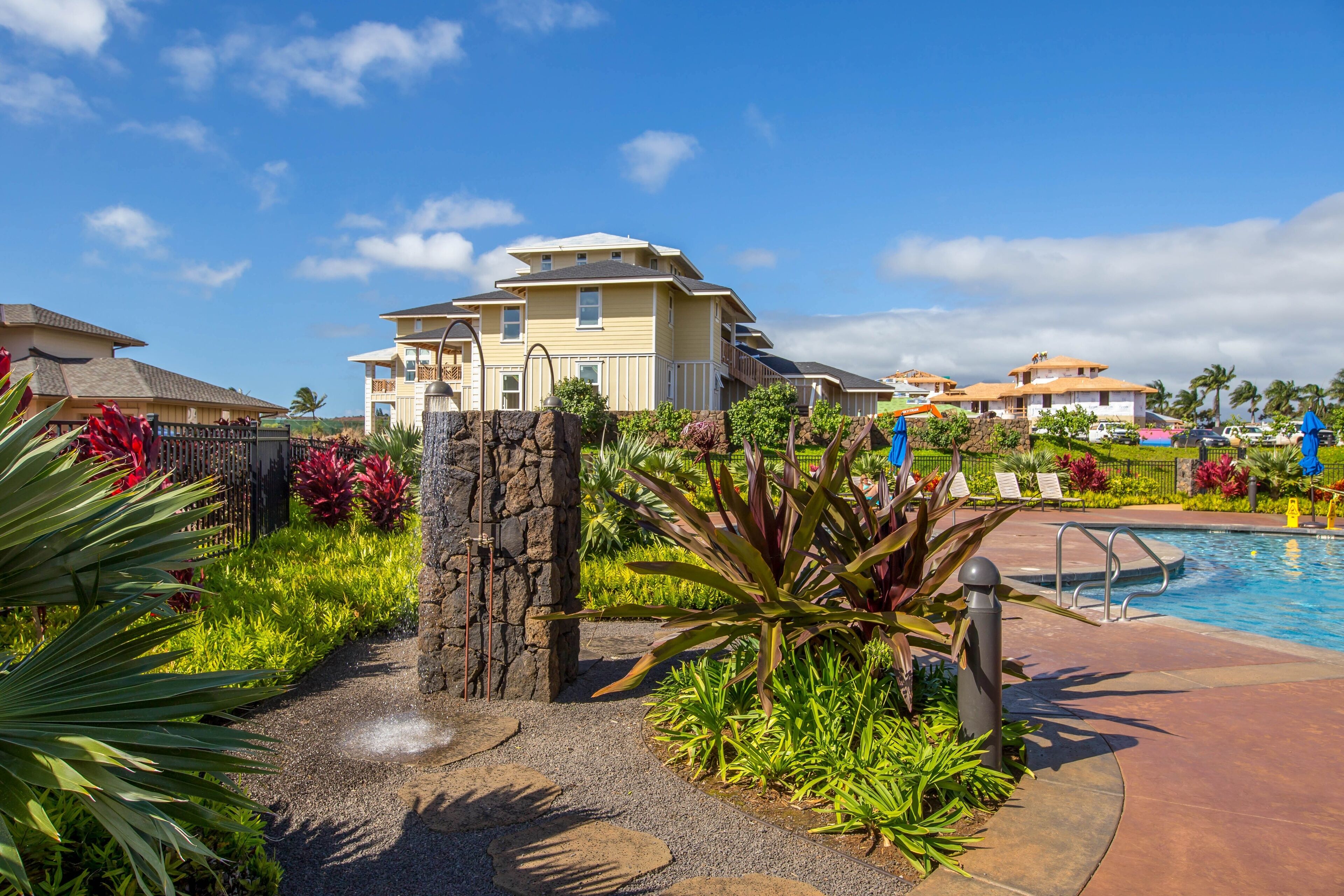A resort with a pool, a stone pathway, and tropical plants.