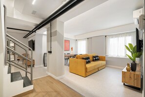 A modern living room with a sofa, a coffee table, and a staircase. - Dobo Madrid Cabrera (Madrid)