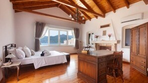 Un dormitorio con techo de madera, una cama, un escritorio y vistas a las montañas.