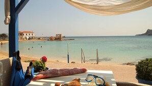 Vista a la playa desde un espacio cubierto con una mesa, una silla y una toalla.