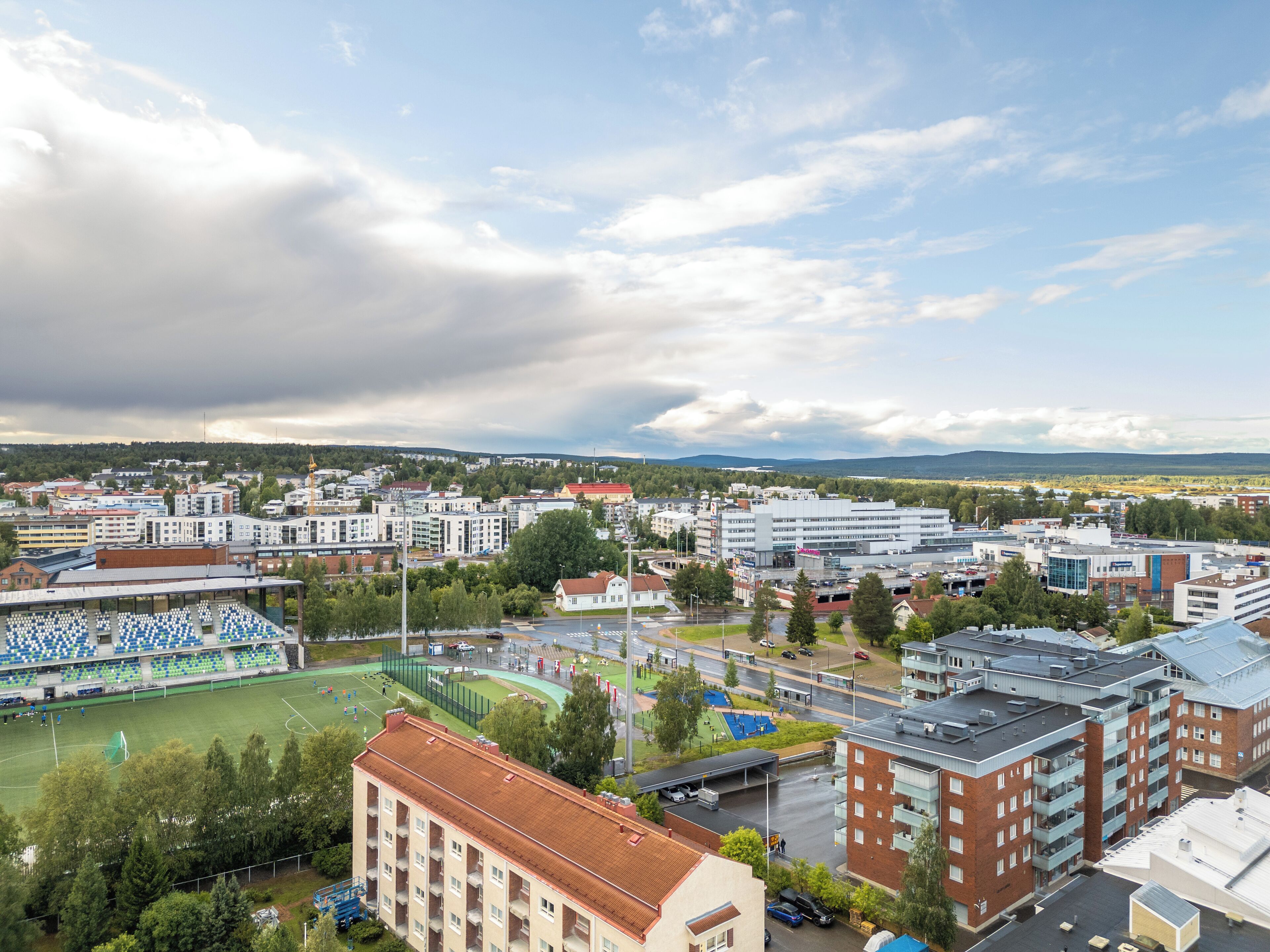 En stadsbild med moderna byggnader, en sportplan och en flod.