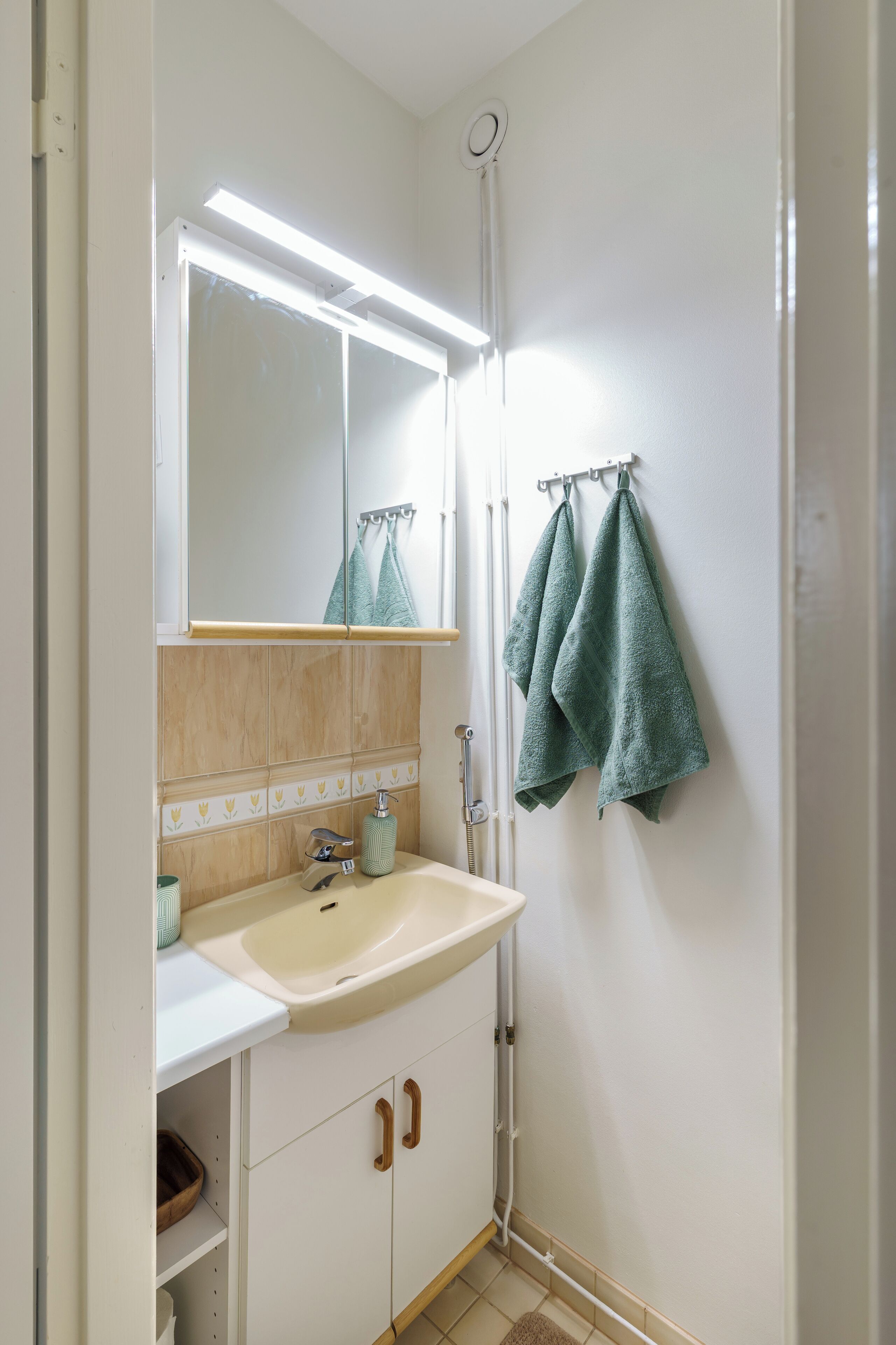 A bathroom with a white sink, a mirror, a towel rack with two towels, and a shower curtain rod.