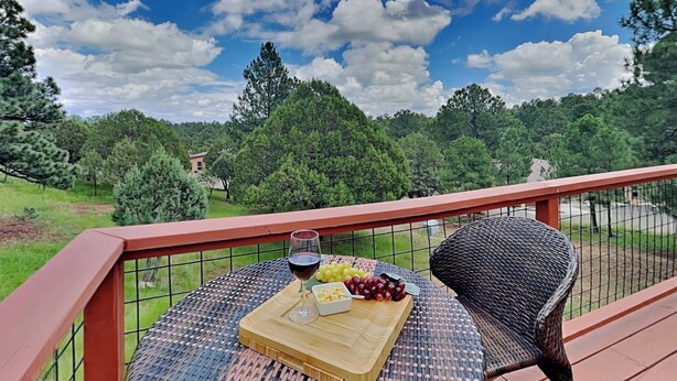 Una terraza con una mesa lista para una comida, una copa de vino tinto y una bandeja de fruta.