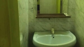 A bathroom with a sink, mirror, and shower enclosure.