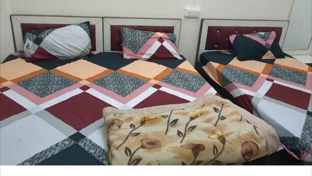 A room with two beds, each with a patterned quilt and pillows.