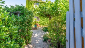 A garden pathway leading to a house with a white fence and lush greenery. - Holiday Home 'Jardin' with Shared Pool, Private Terrace and Wi-Fi (L'Isle-sur-la-Sorgue)