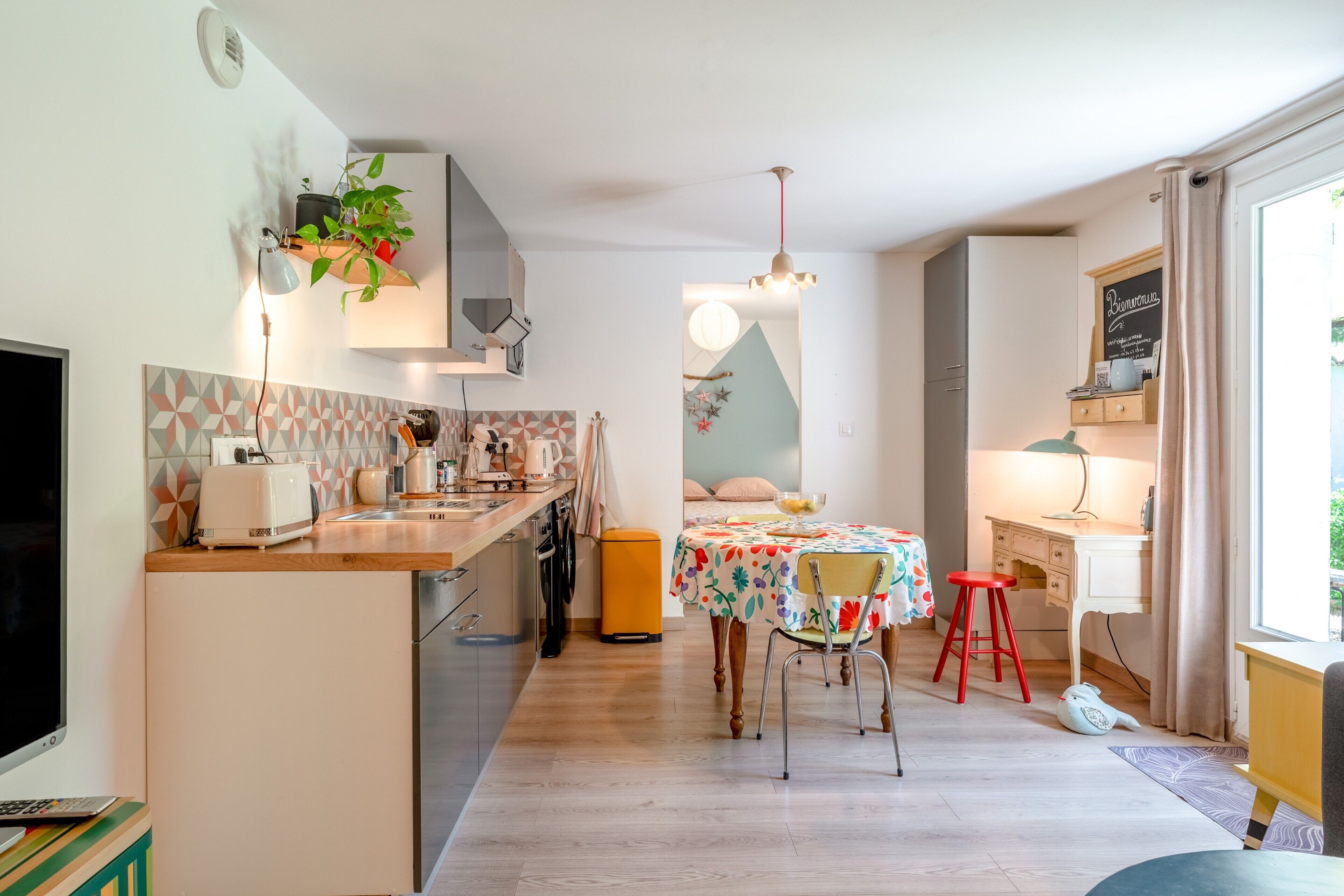 A modern kitchen with a central island, a dining area with a table and chairs, and a workspace with a desk and chair.