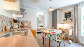 Una cocina moderna con encimera de madera, pileta de acero inoxidable y comedor con mantel floral.
