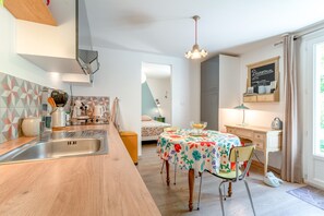 A modern kitchen with a wooden countertop, stainless steel sink, and a dining area with a floral tablecloth. - Holiday Home 'Jardin' with Shared Pool, Private Terrace and Wi-Fi (L'Isle-sur-la-Sorgue)