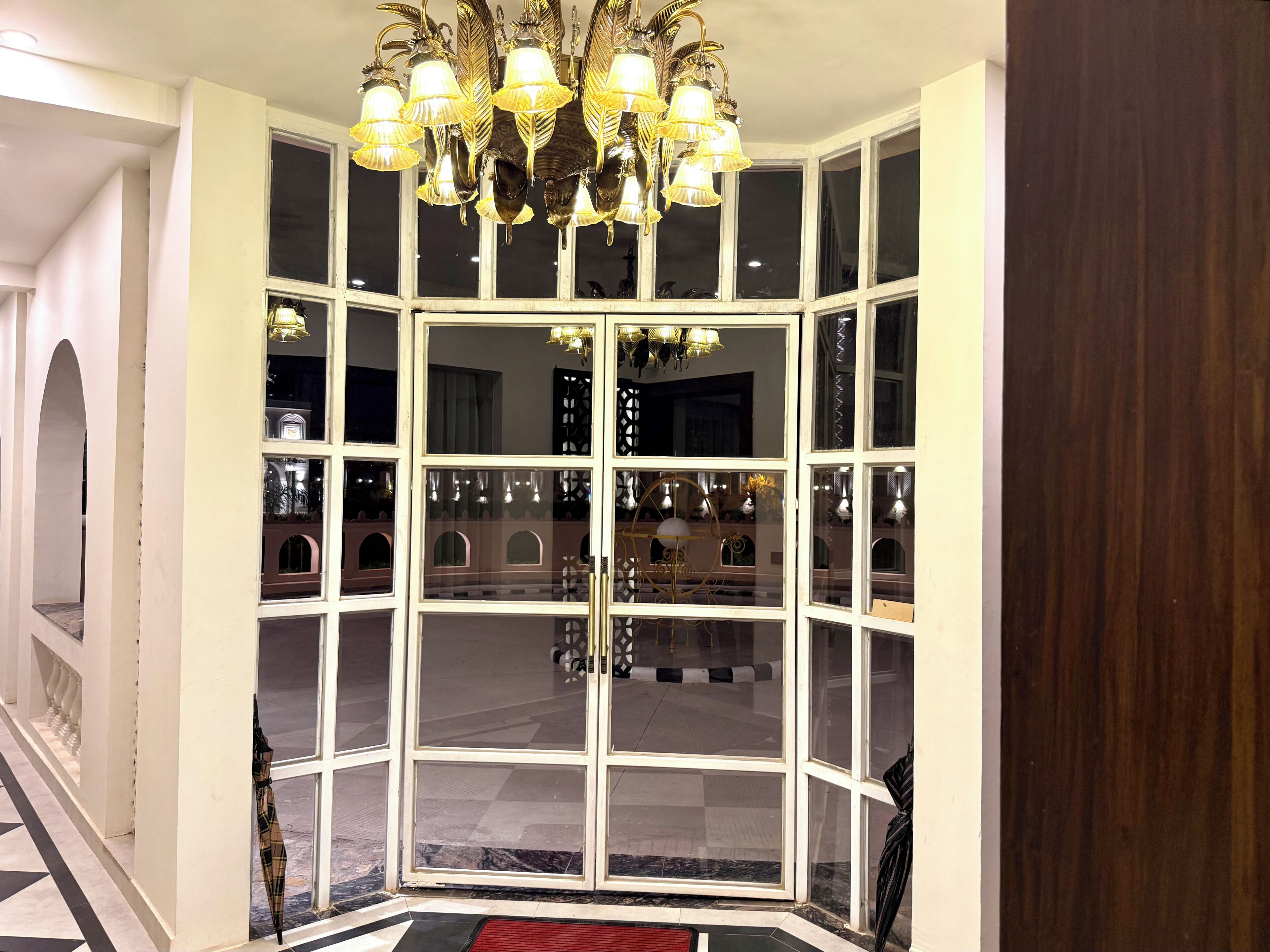 Ein Zimmer mit einem großen Erkerfenster, einer Kristallleuchtre und einem gemusterten Boden.
