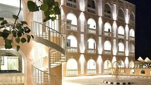 Un edificio con una escalera en espiral, varios ventanales arqueados y un patio.