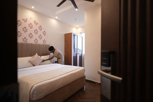 A hotel room with a large bed, a wardrobe, and a television. - Rambagh Resort Gwalior (Gwalior)
