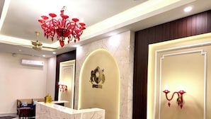 Zona de recepción de un hotel con mostrador de mármol, una araña y un escudo en la pared.