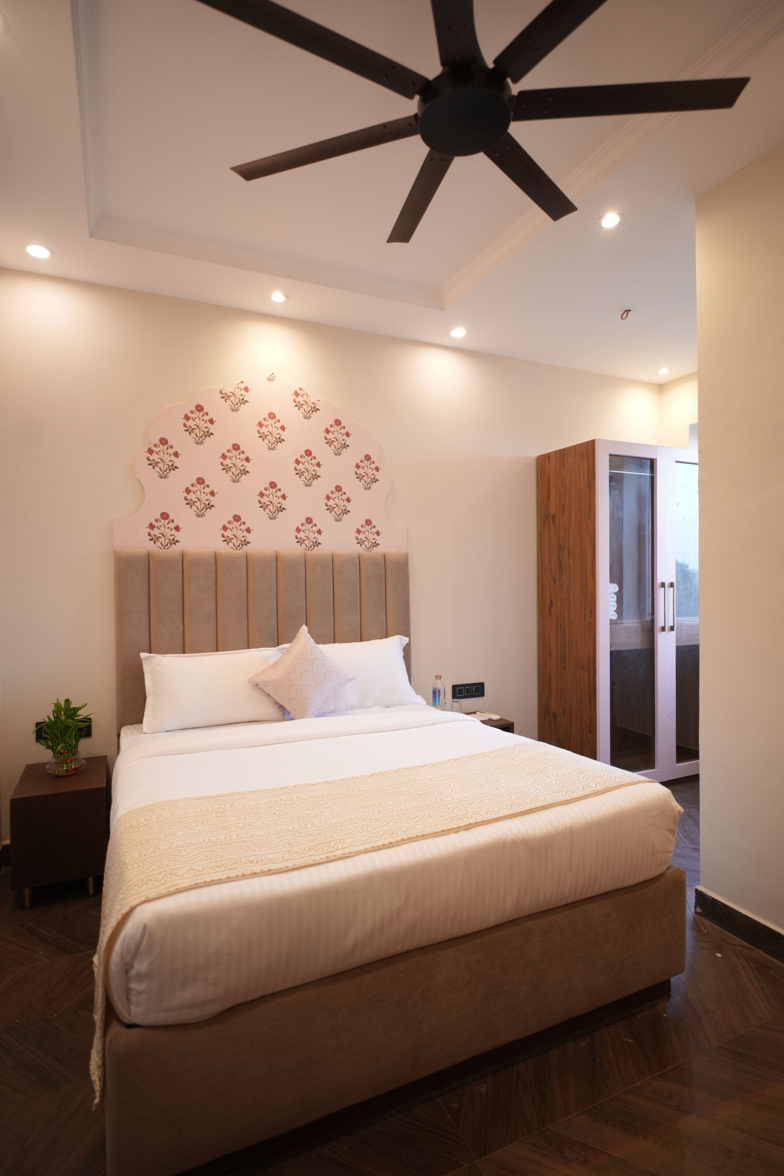 Een moderne slaapkamer met een groot bed, een plafondventilator en een garderobe.