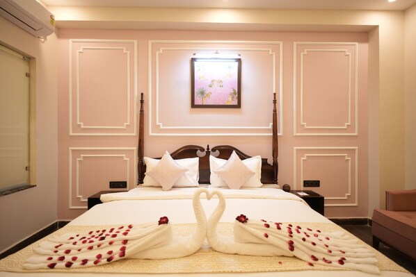 A hotel room with a large bed, a nightstand, a dresser, and a framed picture on the wall. - Rambagh Resort Gwalior (Gwalior)