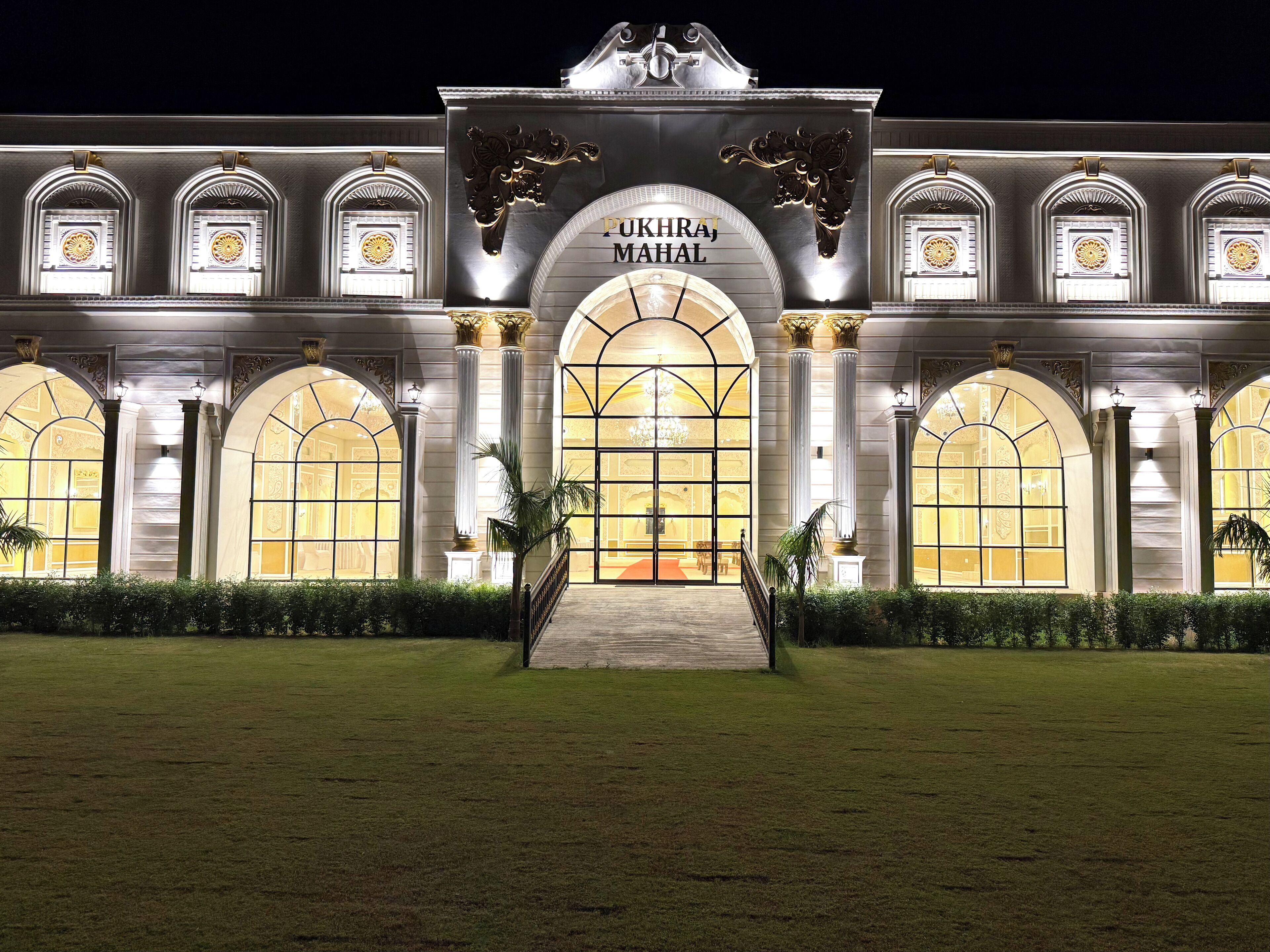 A grand building with a large arched entrance, columns, and a sign that reads "PUKHRA MAHAL".
