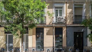 A building with a beige facade, a black door, and a balcony with a black railing. - Dobo Madrid Goya (Madrid)