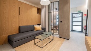 A modern reception area with a sofa, a glass coffee table, wooden paneling, and a large window. - Dobo Madrid Goya (Madrid)
