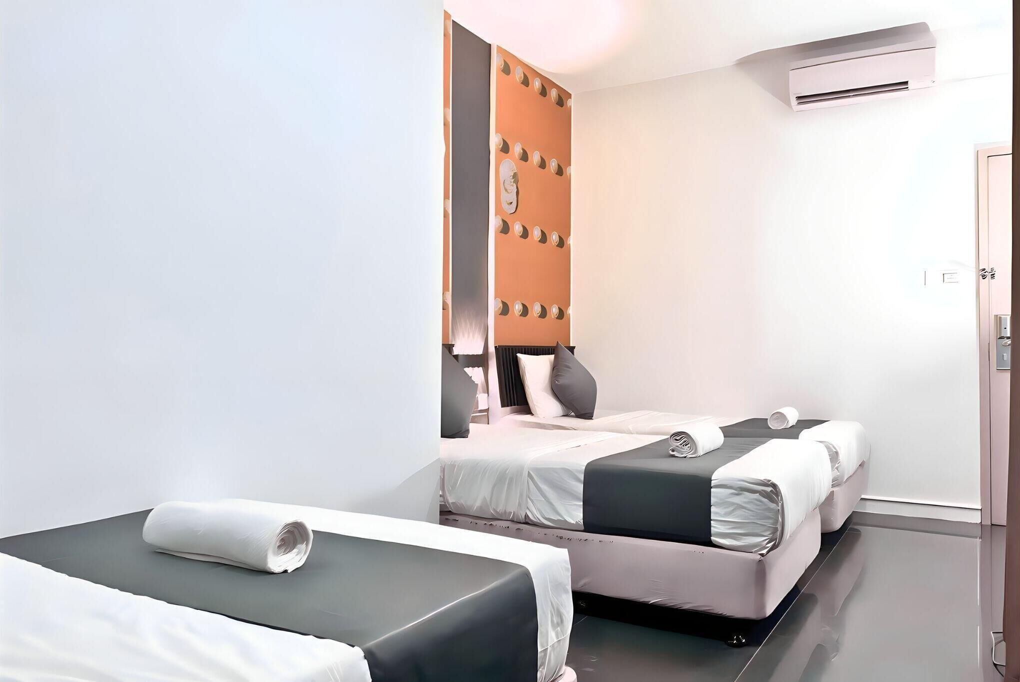 Una habitación de hotel con dos camas, aire acondicionado en la pared y una puerta.