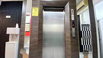 An elevator with a metallic finish, a caution sign, and a CTV security camera.