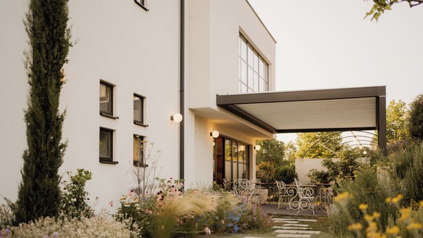 A modern house with a garden, a patio with chairs, and a covered outdoor area. - Adults Only Boutique-Hotel maison 41 (Bad Gleichenberg)