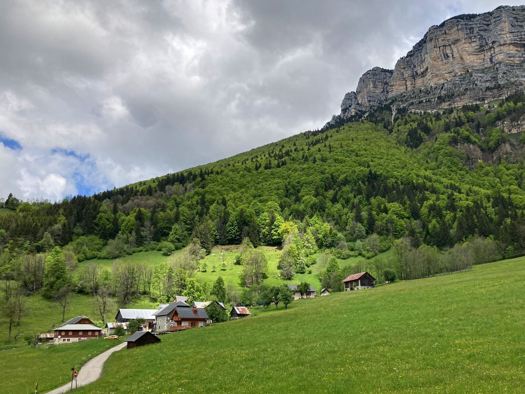 Un paysage rural avec des maisons sur une colline, une montagne en arrière-plan et un ciel dégagé.
