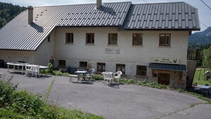 A building with a sign reading 'Bovette,' outdoor seating, and a mountain backdrop. - Cottage "La Ferme de l’Ours" with Mountain View, Private Terrace and Wi-Fi (Entremont-le-Vieux)