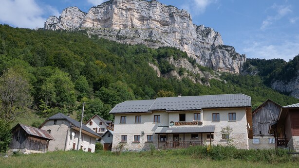 A building with a stone facade, a sign reading 'LA FERME DELOURS,' and a mountain backdrop. - Cottage "La Ferme de l’Ours" with Mountain View, Private Terrace and Wi-Fi (Entremont-le-Vieux)