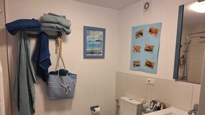 A bathroom with a toilet, sink, and a towel rack with folded towels.