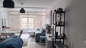 A modern, well-lit room with a bed, a desk, a sofa, and a bookshelf.