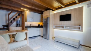 Eine moderne Küche mit integriertem Kühlschrank, Holzbalkendecke, Essbereich mit Bank und einem an der Wand montierten Fernseher.