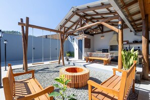 A wooden pergola with a circular fire pit, wooden benches, and a kitchen area with a brick oven. - Comfortable and Sophisticated Accommodations Just Minutes From the Beach - VIL (Penha)